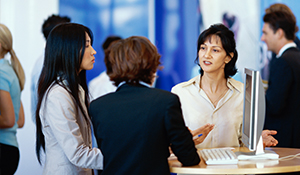 Group of women dressed professionally standing at a high top table talking