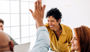 Woman in a yellow blouse giving a high five to a man in a long-sleeved shirt