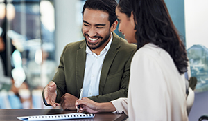 Hispanic man sitting next to a young woman at a table taking notes