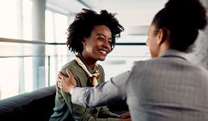 Female professional encouraging another female professional with her hand resting on her shoulder