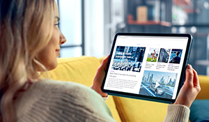 Woman on a yellow couch looking at a tablet screen with several ads