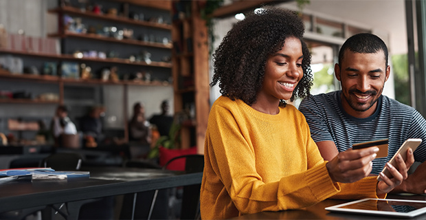 Two people smiling at a phone about to make a purchase