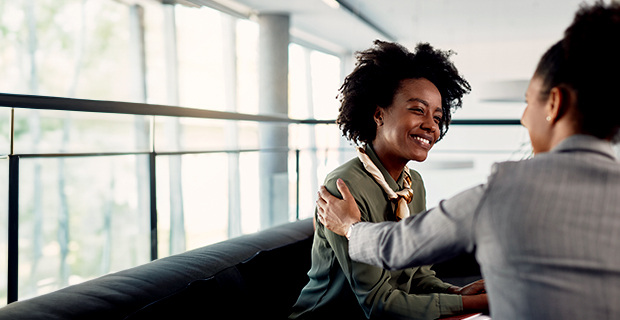 Female professional encouraging another female professional with her hand resting on her shoulder