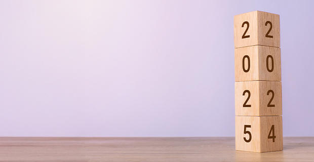 A stack of four wooden blocks. The top three blocks show '202' while the bottom block is transitioning between '5' and '4', symbolizing the change from the year 2024 to 2025.