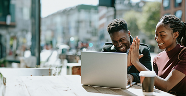 a man and a woman with a laptop high fiving 