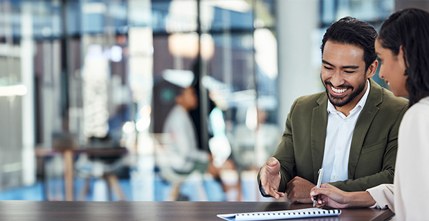 Hispanic man sitting next to a young woman at a table taking notes