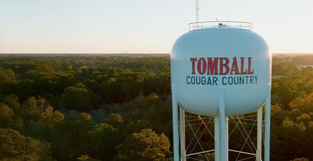 A large white water tower with red and blue lettering that reads 